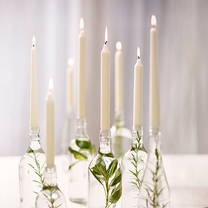 Stilvoll und natürlich dekoriert: Bolsius Professional Tafelkerzen und Spitzkerzen in Glasflaschen mit frischem Grün sorgen für eine elegante, ruhige Atmosphäre bei besonderen Anlässen oder im Alltag.