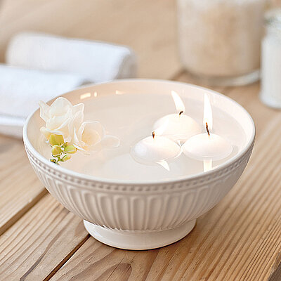 Drei weiße Schwimmkerzen treiben sanft in einer edlen Schale mit Wasser – ideal für beruhigende Momente und stilvolle Tischdekoration.